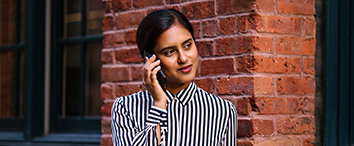 Picture of woman standing next to the brick wall and talking on phone