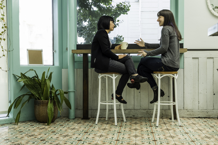 Two woman sitting near table